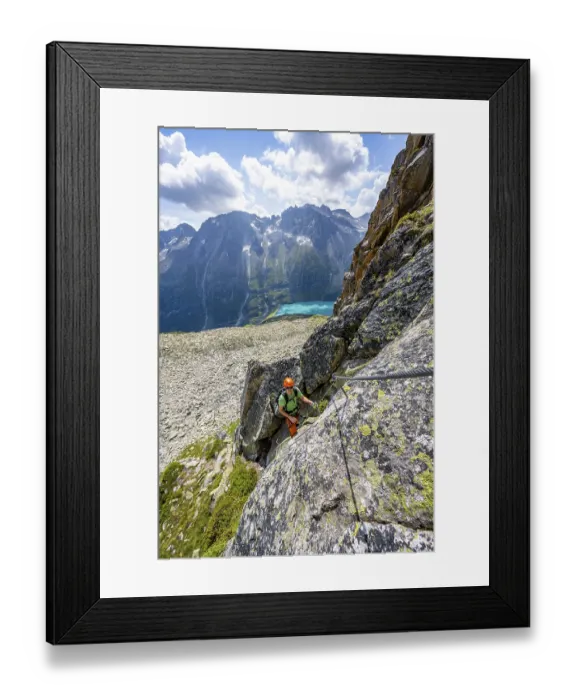 Framed Print : Mountaineer climbs on steep rock face in the secured via ferrata Crocodile Mountain Lake at Bergseeschijen-Vorbau