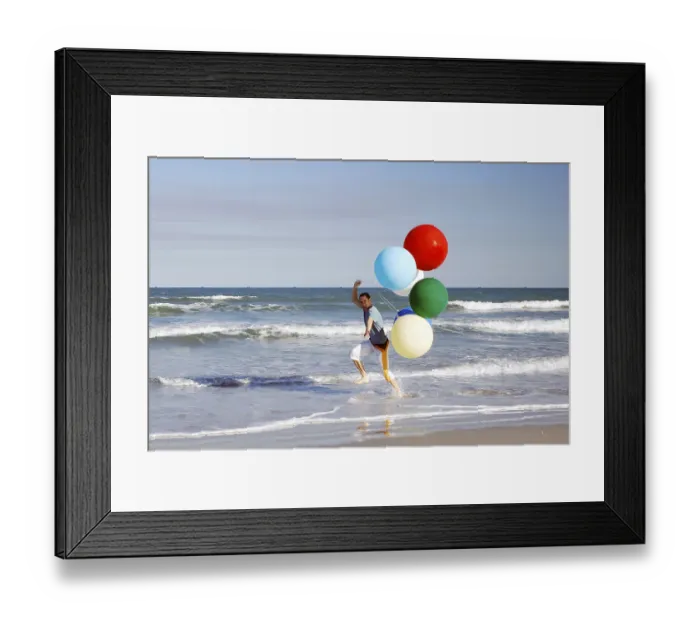 Framed Print : Young man with large colourful balloons at the beach