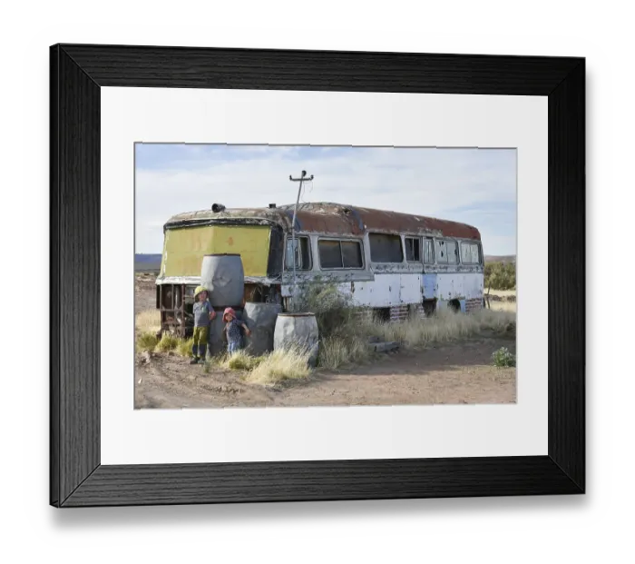 Framed Print : Boy and girl play at car wreck of an old bus