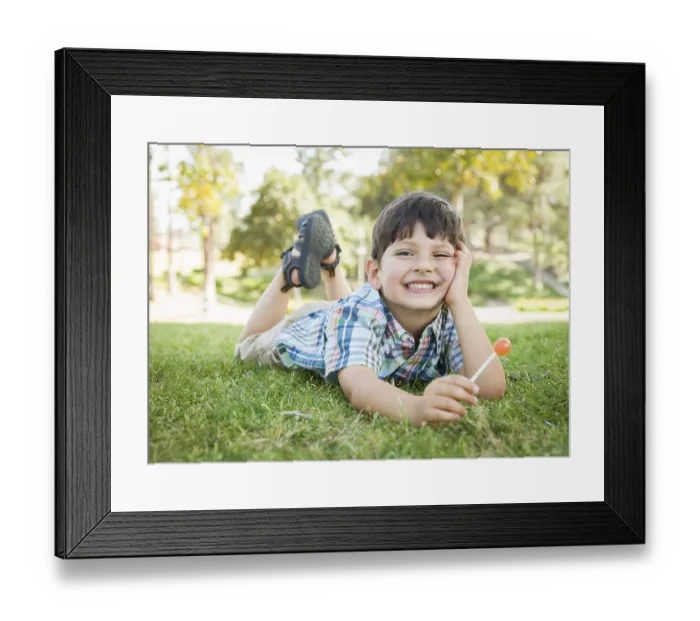 Framed Print : Handsome young boy enjoying his lollipop outdoors on the grass