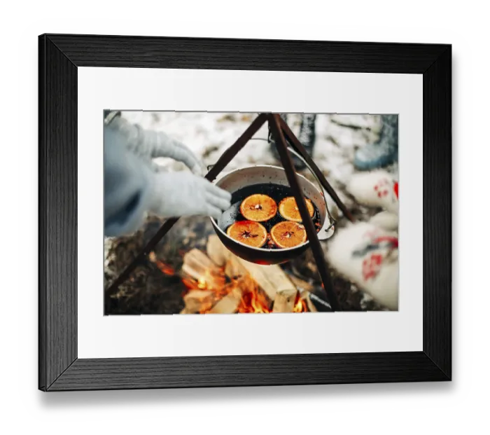 Framed Print : From above traditional mulled wine with slices of orange preparing in pot over burning logs in winter in countryside