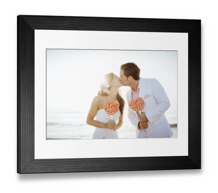 Framed Print : Bride and groom kissing, heart-shaped lollipops in their hands Framed Print : Bride and groom kissing, heart-shaped lollipops in their hands