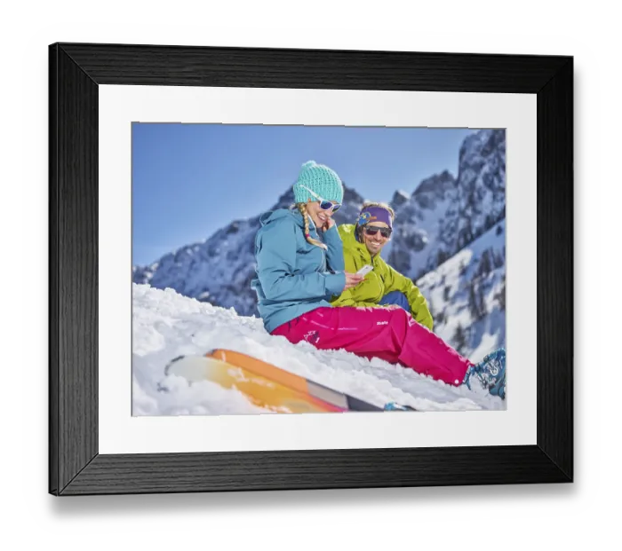 Framed Print : Skiers sitting in the snow taking a break