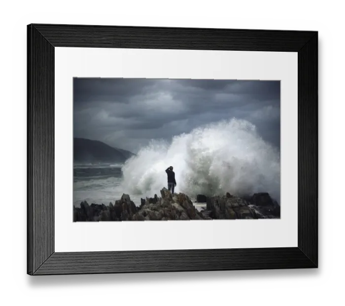 Framed Print : Man on rock in front of breaking wave