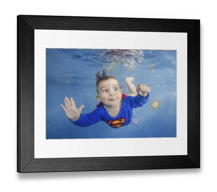 Framed Print : Little boy in a superman costume dives underwater in the pool