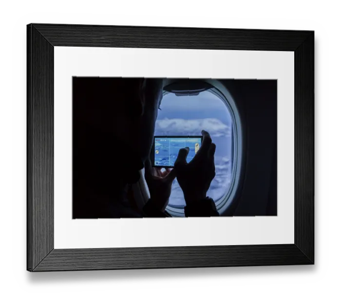 Framed Print : Silhouette of a man taking photos of the mountains using a smartphone from an airplane window Framed Print : Silhouette of a man taking photos of the mountains using a smartphone from an airplane window