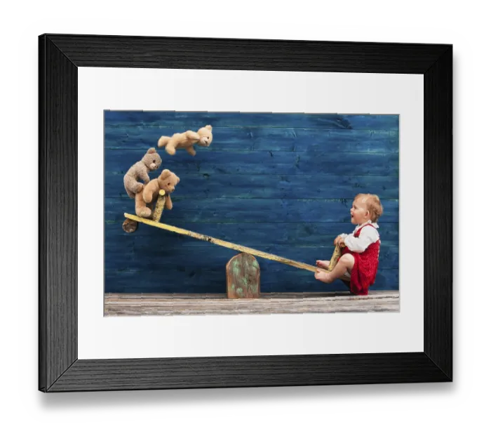 Framed Print : Three-year-old girl with teddy bear on seesaw