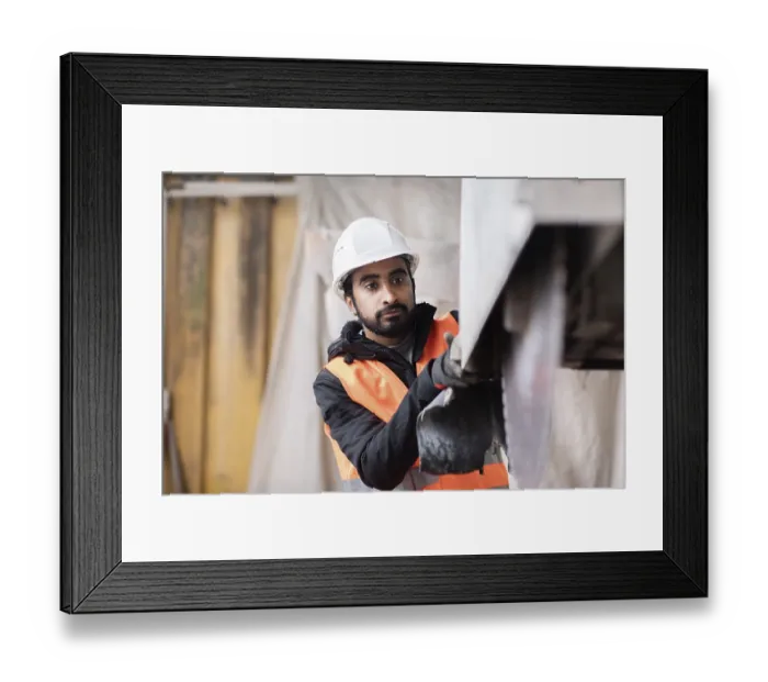 Framed Print : Technician with beard and helmet works in a workshop