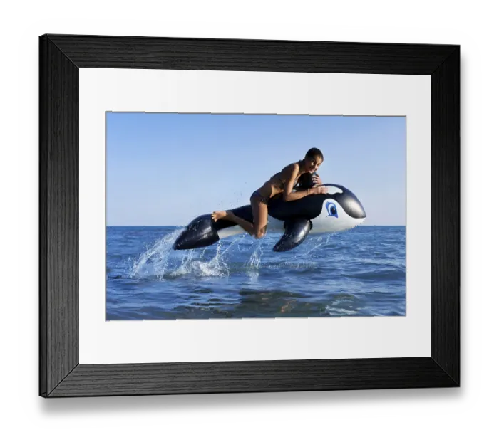 Framed Print : Girl sitting on inflatable orca jumping in the sea