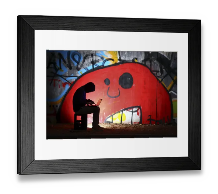 Framed Print : Man surfing on a laptop computer in front of a graffiti covered wall