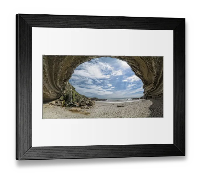 Framed Print : Woman wandering through the mighty rock overhang of Truman's Cove on the beach with a waterfall