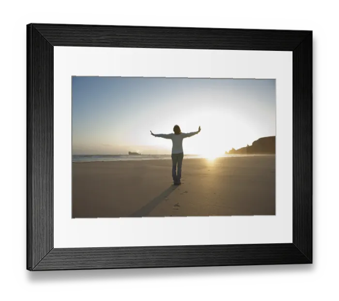 Framed Print : Woman relaxing with her arms outstretched on the beach in the evening