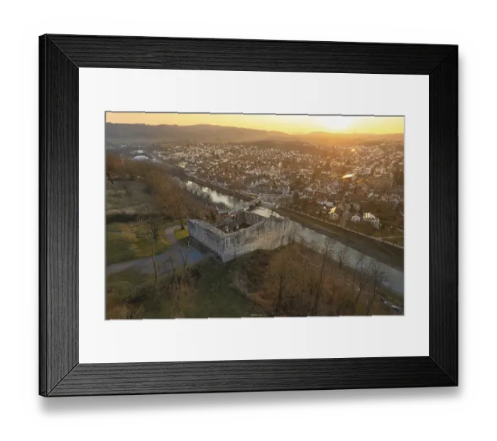 Framed Print : Medieval castle on a river surrounded by a town at sunset