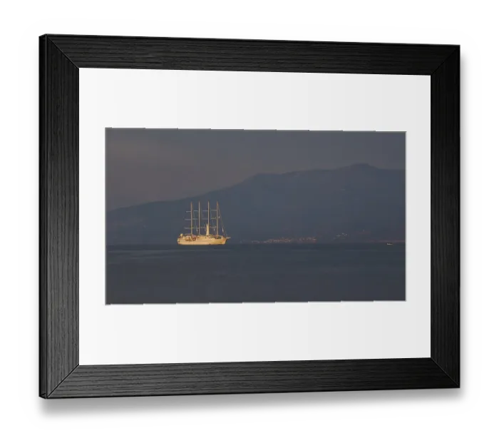 Framed Print : A large sailing ship sails in calm seas against a mountain backdrop at dusk
