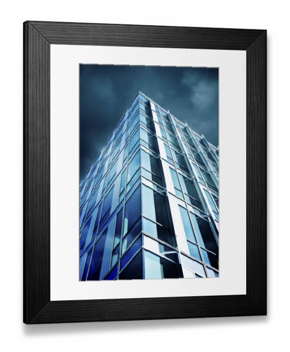 Framed Print : A modern skyscraper with a glass facade reflecting the cloudy sky