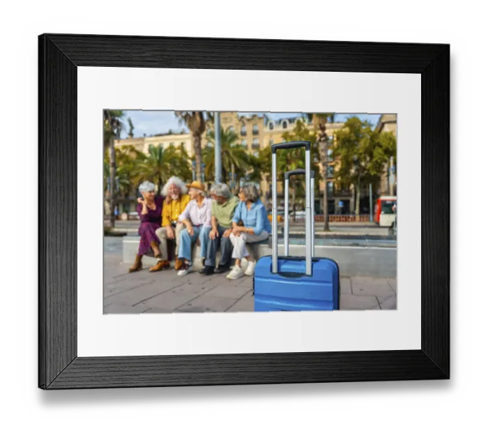 Framed Print : Seniors group relaxing on a bench in a city street with a blue suitcase in the foreground