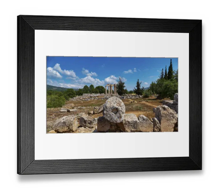 Framed Print : Ancient temple columns in an open field with surrounding trees and mountains in the background