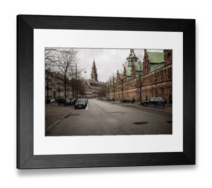 Framed Print : A cobblestone street with historical buildings and a cloudy sky in Copenhagen