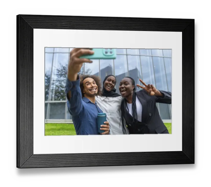 Framed Print : Three diverse friends smiling and laughing while taking a group selfie with a smartphone Framed Print : Three diverse friends smiling and laughing while taking a group selfie with a smartphone