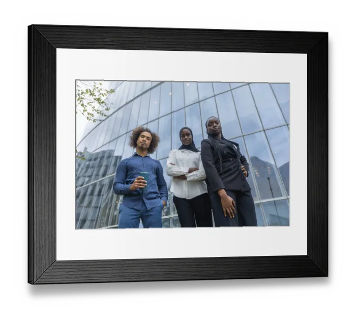 Framed Print : Diverse business team of young professionals standing together with confident expressions against a backdrop of a