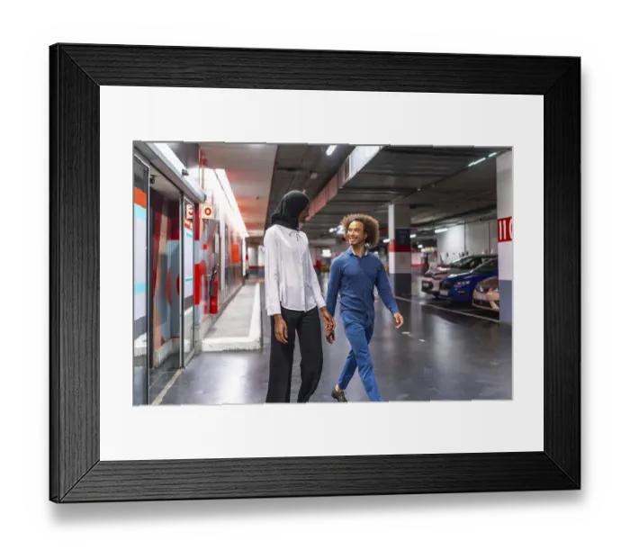 Framed Print : Diverse young couple walking hand in hand through an underground parking garage Framed Print : Diverse young couple walking hand in hand through an underground parking garage