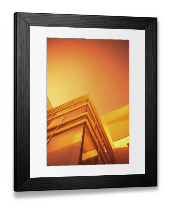 Framed Print : A modern building with glass surfaces under an orange sky Framed Print : A modern building with glass surfaces under an orange sky