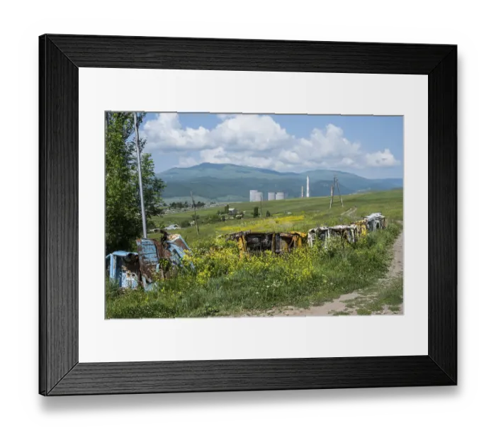 Framed Print : Rusty vehicles stand in a meadow in front of a wooded mountain panorama Framed Print : Rusty vehicles stand in a meadow in front of a wooded mountain panorama