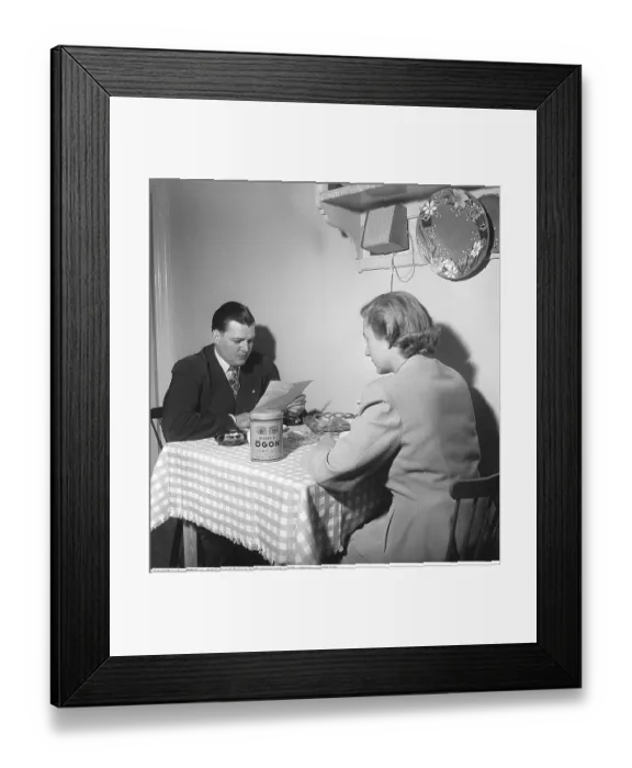 Framed Print : Couple at a Table in the 1950s A couple sits opposite each other at a small dining table