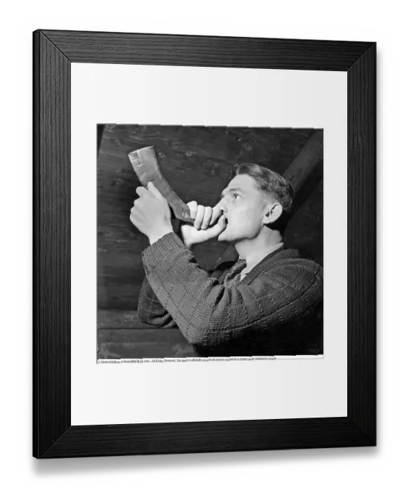 Framed Print : A man is seen blowing into a horn crafted from an animal's horn Framed Print : A man is seen blowing into a horn crafted from an animal's horn