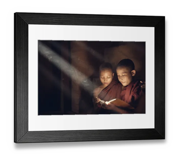 Framed Print : Southeast Asian novice monk reading book inside monastery