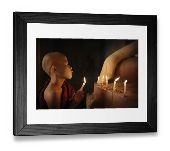 Framed Print : Portrait of young novice monk praying with candlelight inside a Buddhist temple