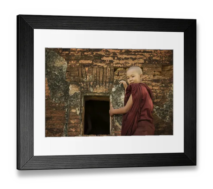 Framed Print : Young novice monk standing outside Buddhist temple