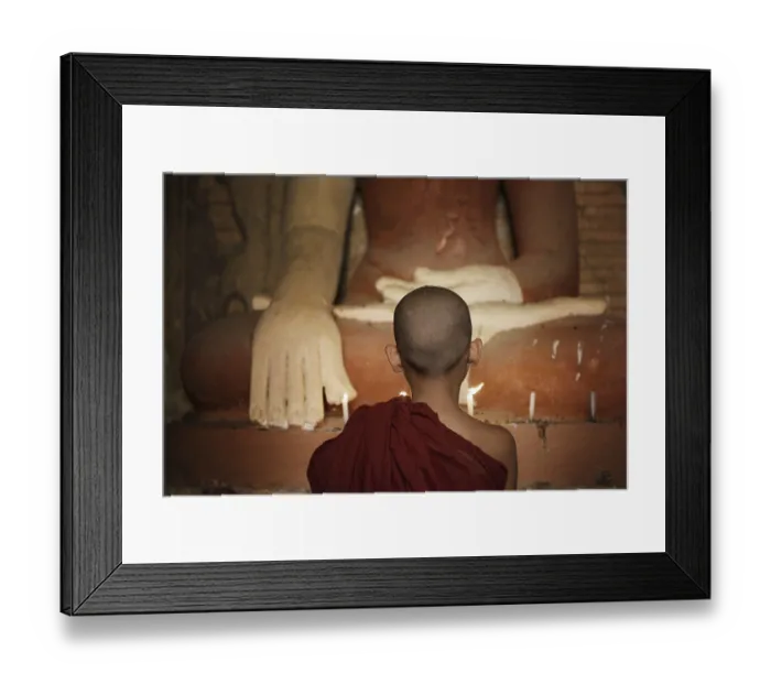 Framed Print : Rear view of young novice monk praying with candlelight inside a Buddhist temple