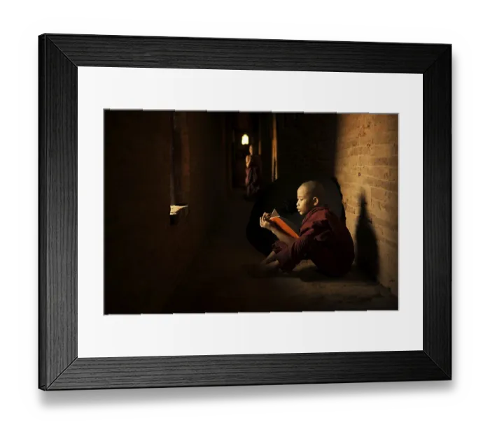 Framed Print : Young Buddhist novice monk reading book inside monastery Framed Print : Young Buddhist novice monk reading book inside monastery