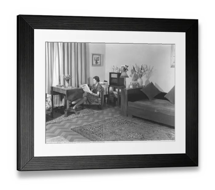 Framed Print : Home life in 1941. A woman sits reading the daily newspaper Falbygdens Tidning in a modestly furnished room