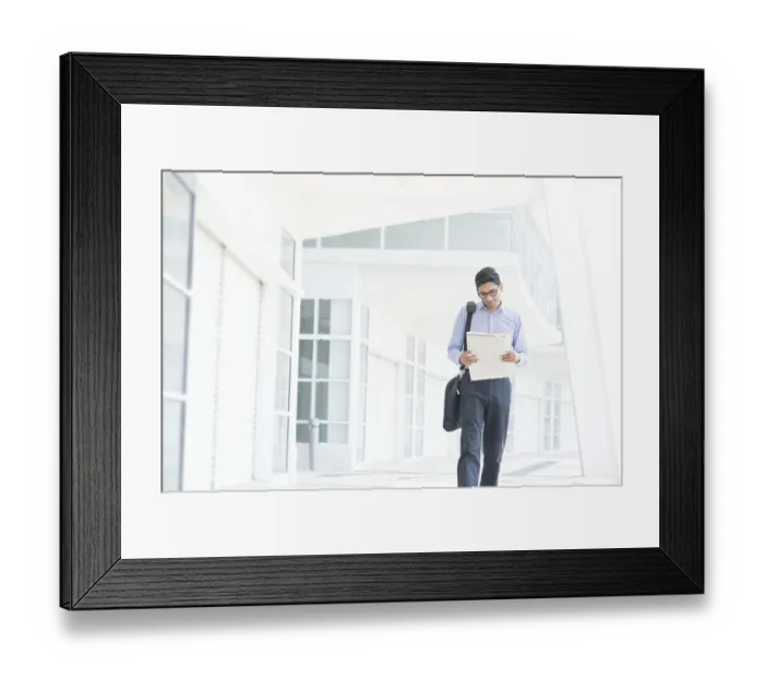 Framed Print : Young Asian Indian businessman reading on news paper while walking to office in morning Framed Print : Young Asian Indian businessman reading on news paper while walking to office in morning