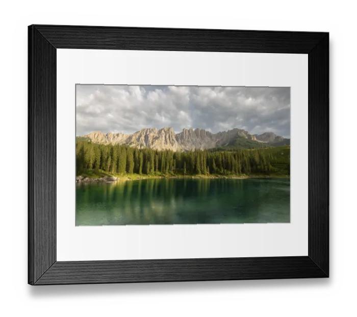 Framed Print : A clear lake (lake Carezza) reflects a dense spruce forest (Picea abies) and majestic mountains under a cloudy sky Framed Print : A clear lake (lake Carezza) reflects a dense spruce forest (Picea abies) and majestic mountains under a cloudy sky