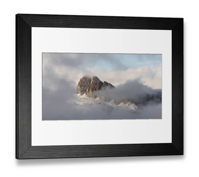 Framed Print : Mountains shrouded in light clouds under a sky flooded with light at the Passo di Falzarego