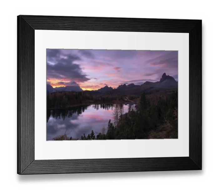 Framed Print : Ein ruhiger Bergsee, umgeben von Waldern und Bergen wahrend des Sonnenaufgangs mit rosa und lila Wolken