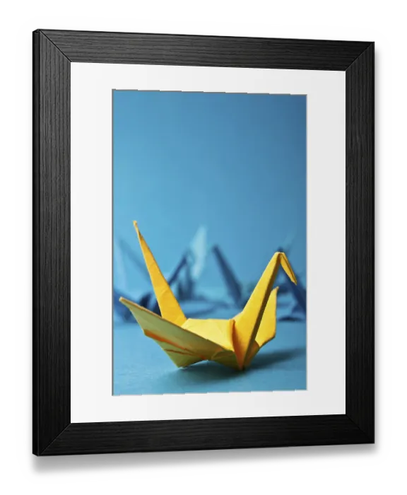 Framed Print : Yellow origami crane on a blue background with other blurry cranes