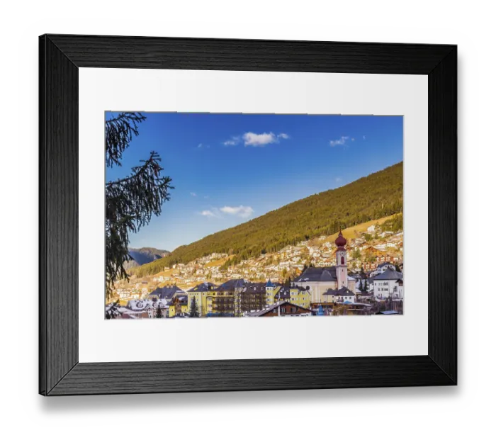 Framed Print : Snowy alpine village in Italy illuminated by sun with mountains in the background
