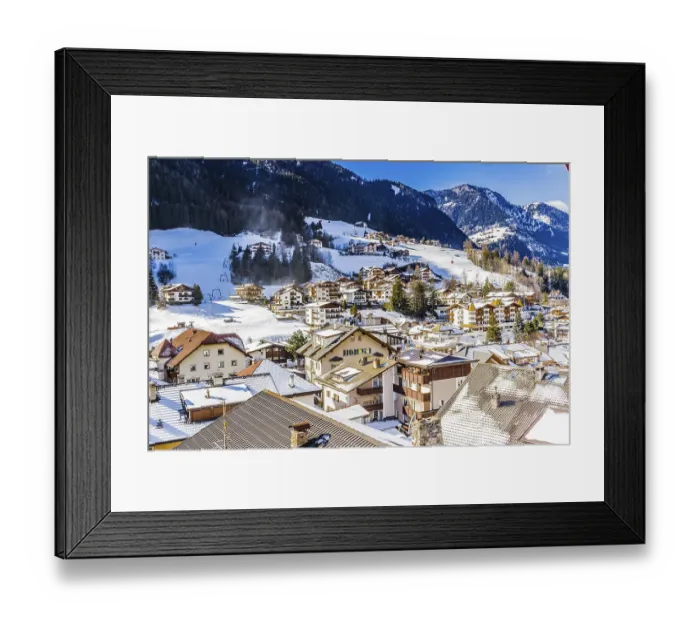 Framed Print : Snowy alpine village in Italy illuminated by sun with mountains in the background Framed Print : Snowy alpine village in Italy illuminated by sun with mountains in the background