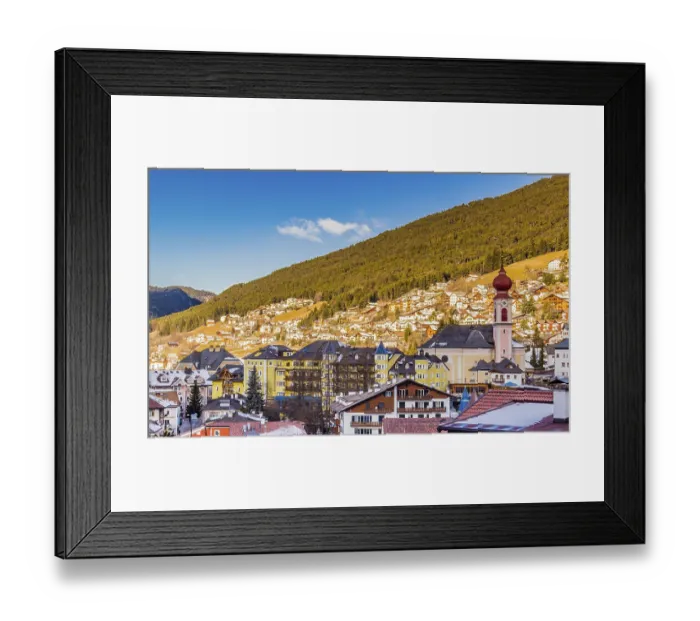 Framed Print : Snowy alpine village in Italy illuminated by sun with mountains in the background Framed Print : Snowy alpine village in Italy illuminated by sun with mountains in the background