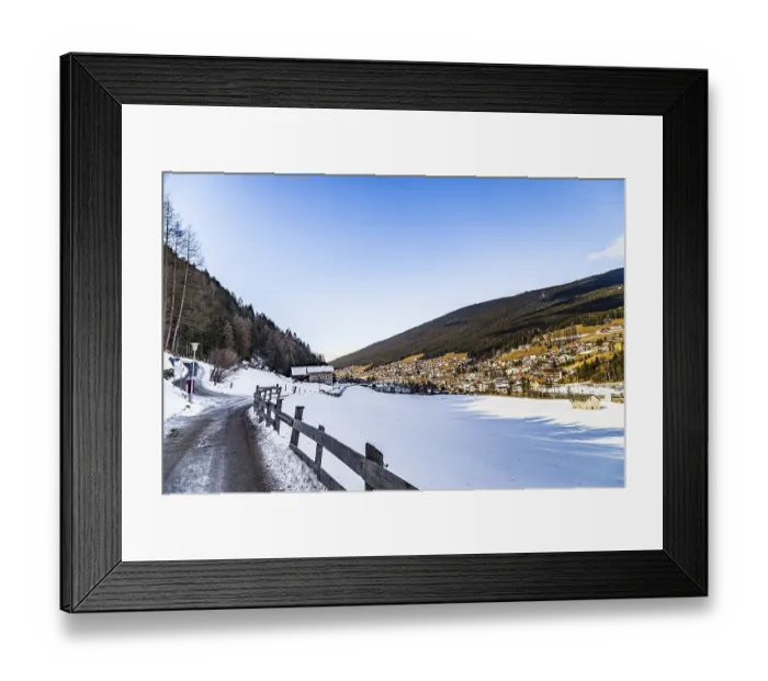 Framed Print : Snowy alpine village in Italy illuminated by sun with mountains in the background