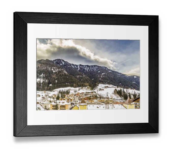 Framed Print : Snowy alpine village in Italy illuminated by sun with mountains in the background