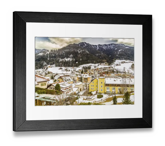 Framed Print : Snowy alpine village in Italy illuminated by sun with mountains in the background