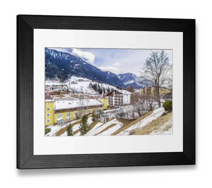 Framed Print : Snowy alpine village in Italy illuminated by sun with mountains in the background