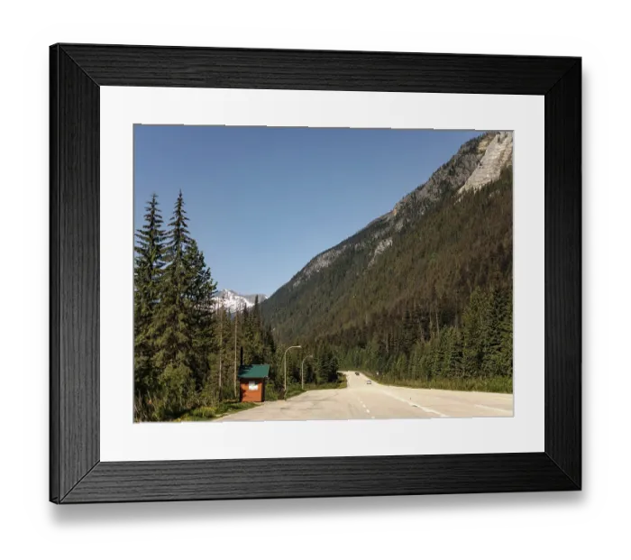 Framed Print : Empty road stretches through a forest with towering mountains on the Trans Canada Highway in British Columbia