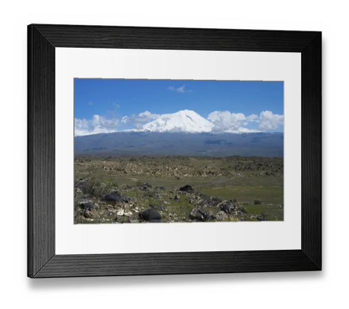 Framed Print : Peaceful landscape with snow-covered mountain and rocky plains under blue sky