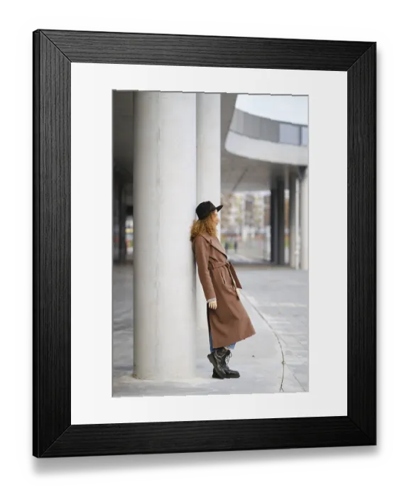 Framed Print : A woman stands leaning against a concrete column in an urban setting Framed Print : A woman stands leaning against a concrete column in an urban setting
